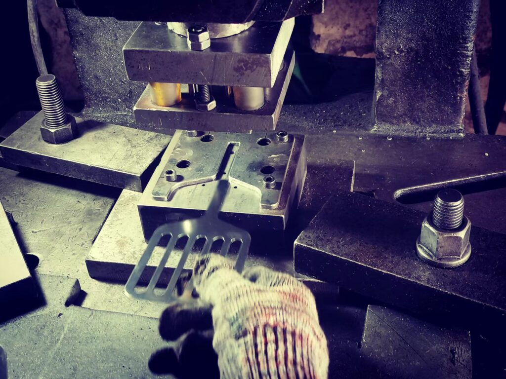 worker holding a metal turner head to a mold planing for stamping